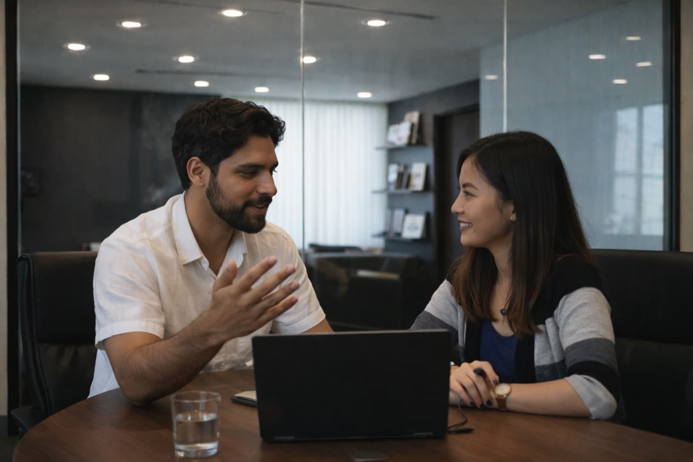 Two colleagues in discussion across a laptop
