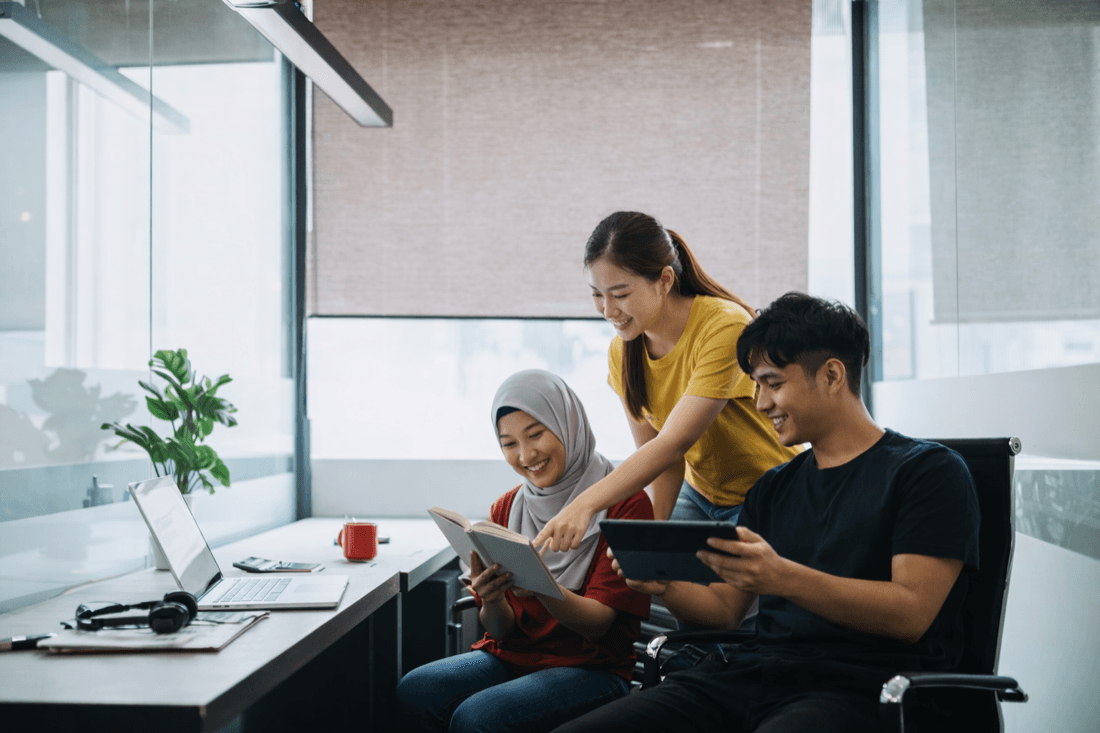 Three colleagues reviewing work together at a desk